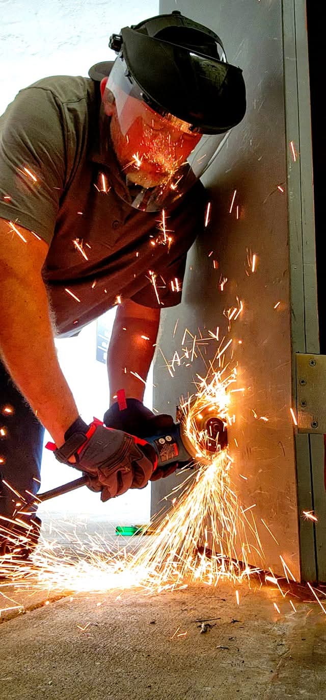 Rick at work cutting a metal door frame with an angle grinder